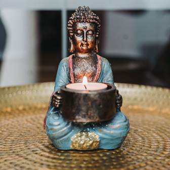 Lassen Sie sich in eine Welt voller sinnlicher Entspannung entführen Eine Buddha-Statue die ein Teelicht hält.