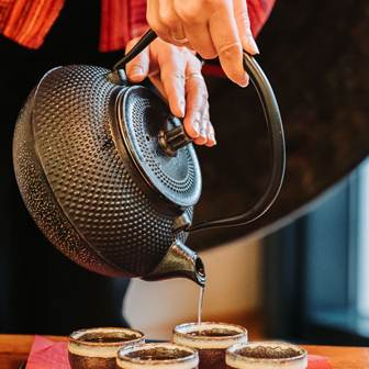 Harmonie für Körper und Geist im Asia Resort Linsberg Tee wird von einer gusseisernen Kanne in kleine Tassen gegossen.