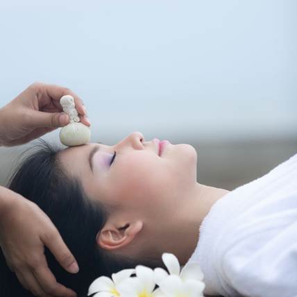 Traditionelle thailändische Kräuterweisheit vereint mit moderner, sanfter Pflege Eine Frau bekommt eine Gesichtsbehandlung.